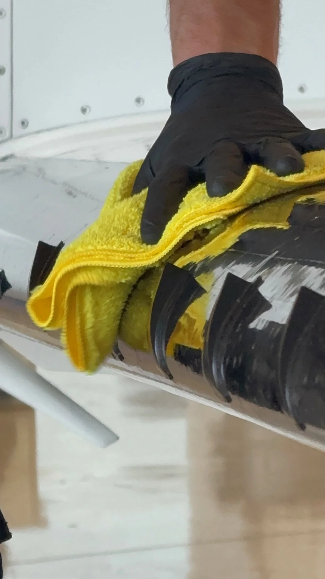 Technician cleaning aircraft de-ice boot with microfiber cloth